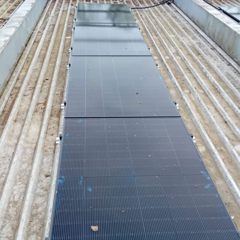 The image shows a set of solar panels installed on a ribbed metal rooftop. The image shows a set of solar panels installed on a ribbed metal rooftop.
